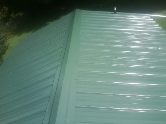 New green metal panels meeting at the ridge of a roof — Flat Roof Repair work by our crew in Windom