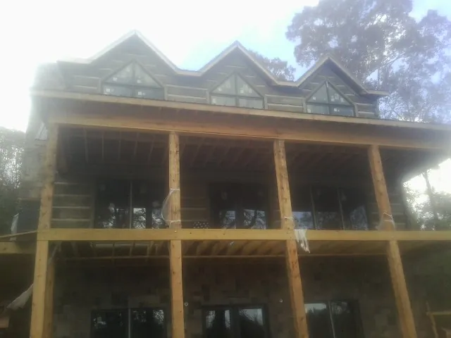 Dormers and porch framing on a large log home under construction — Roof Coating work by our crew in Windom