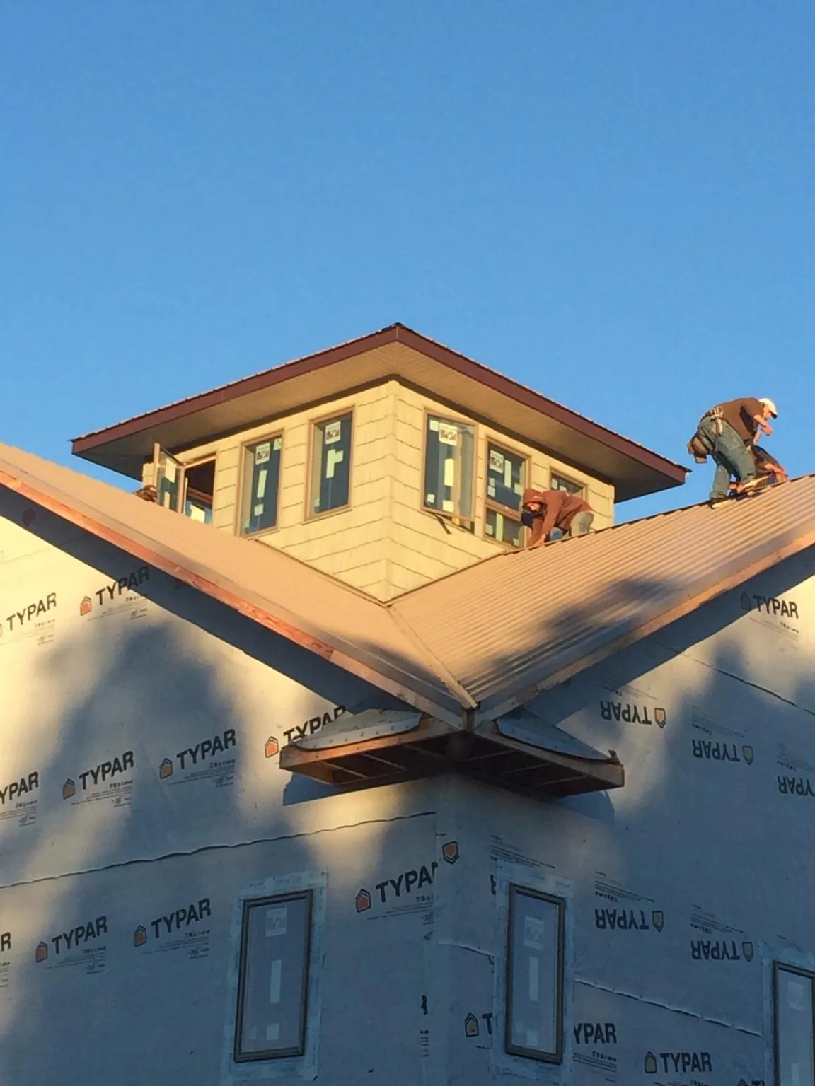 Roofers working around a rooftop cupola on a new metal roof at sunset — Roof Waterproofing in Windom by Roofing Brothers